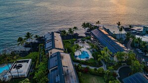A resort with multiple buildings, a swimming pool, and a view of the ocean at sunset. - Kona Makai 3302 2 Bedroom Condo (Kailua-Kona)
