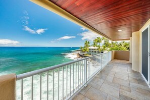 A balcony with a view of the ocean, a wooden ceiling, and a tiled floor.