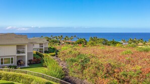 A two-story residential building with a balcony, a lawn, and a view of the ocean. - Na Hale O Keauhou G4 3 Bedroom Condo (Kailua-Kona)