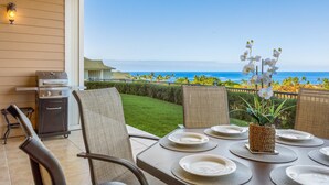 A patio with a grill, dining table set for four, and a view of the ocean. - Na Hale O Keauhou G4 3 Bedroom Condo (Kailua-Kona)