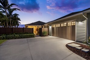 A residential house with a garage, palm trees, and a driveway.