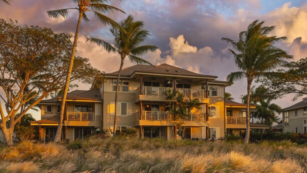 A multi-story beachfront property with balconies, palm trees, and a grassy foreground. - Waikoloa Beach Villas #o23 2 Bedroom Condo (Waikoloa)