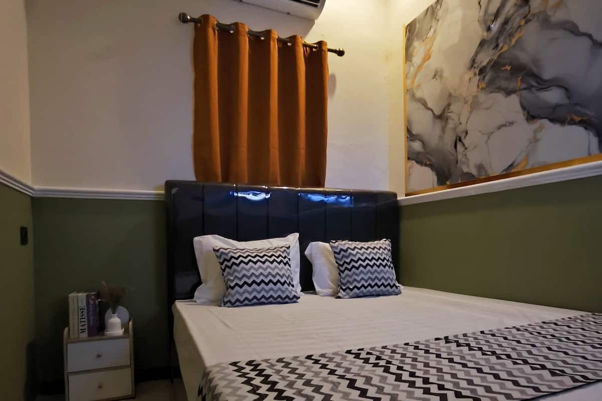 Una camera da letto con un letto, un comodino, un condizionatore e un quadro appeso al muro.