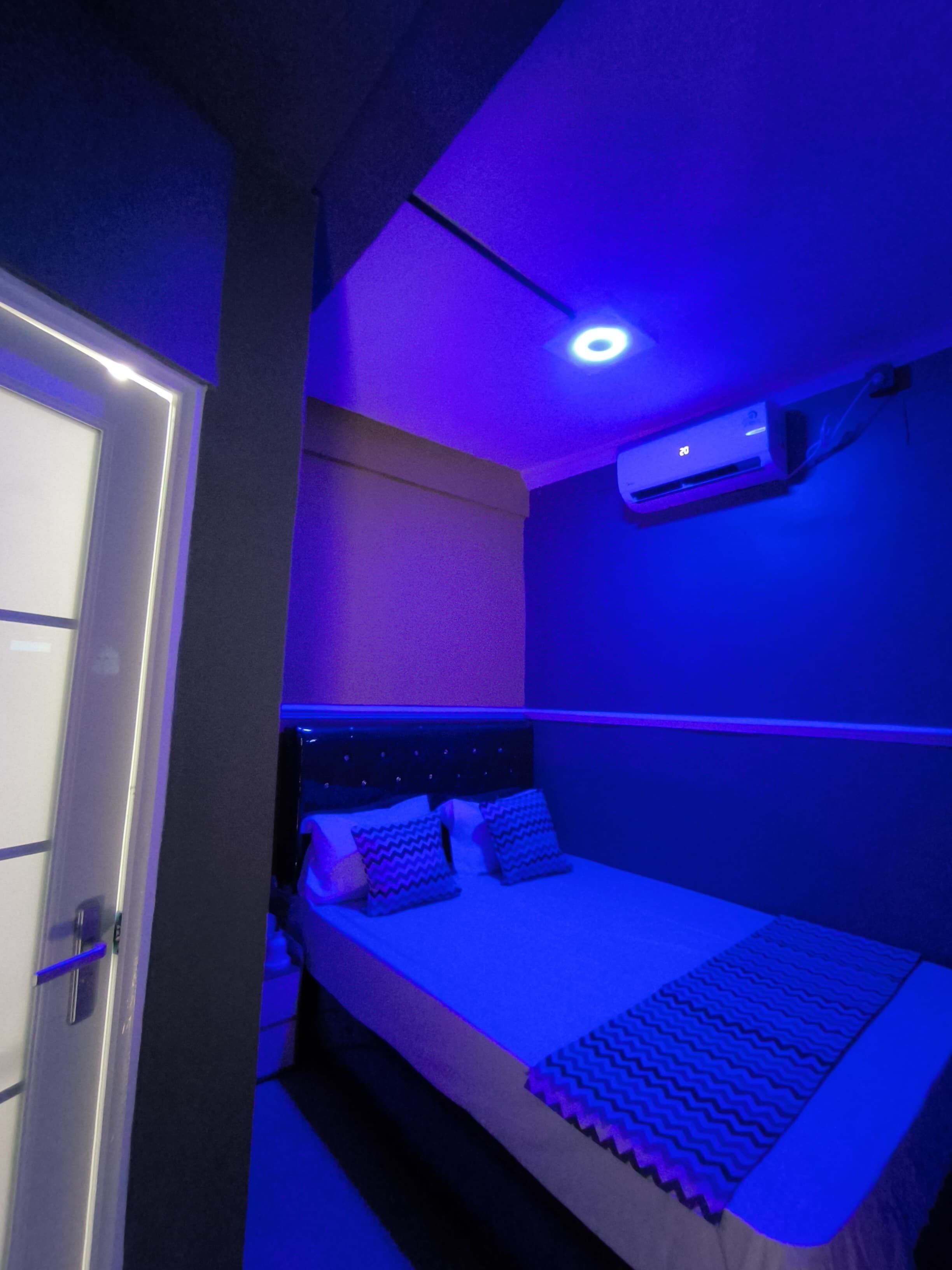 Una habitación con una cama, aire acondicionado y una puerta.
