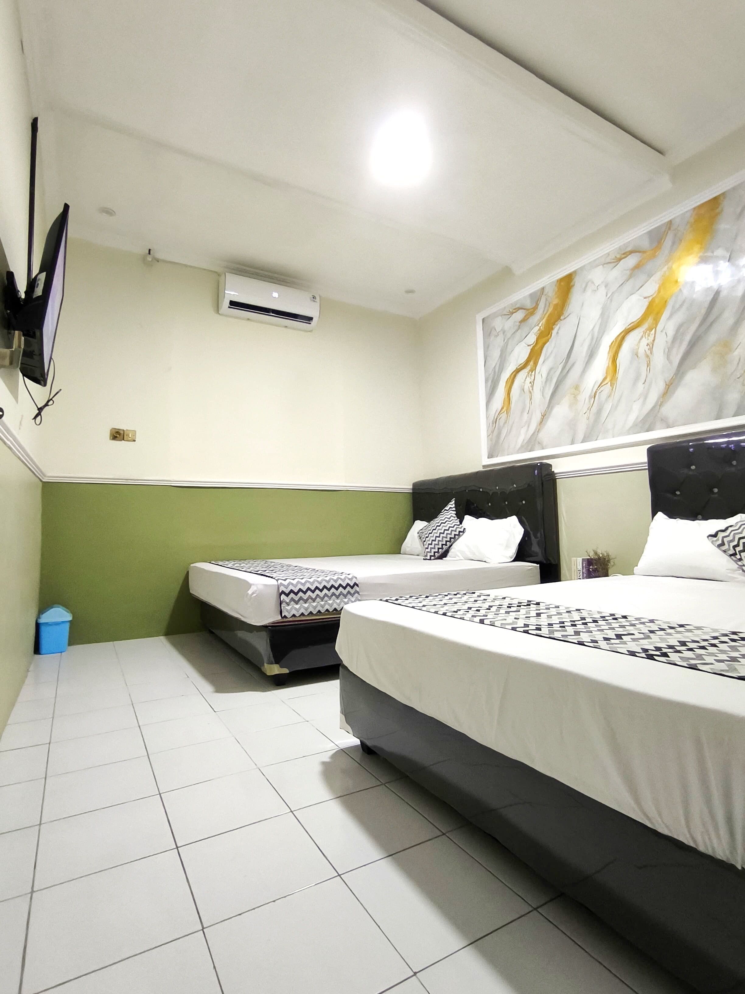 Habitación de hotel con dos camas, un espejo grande, un equipo de aire acondicionado y una pared con diseño que simula mármol.