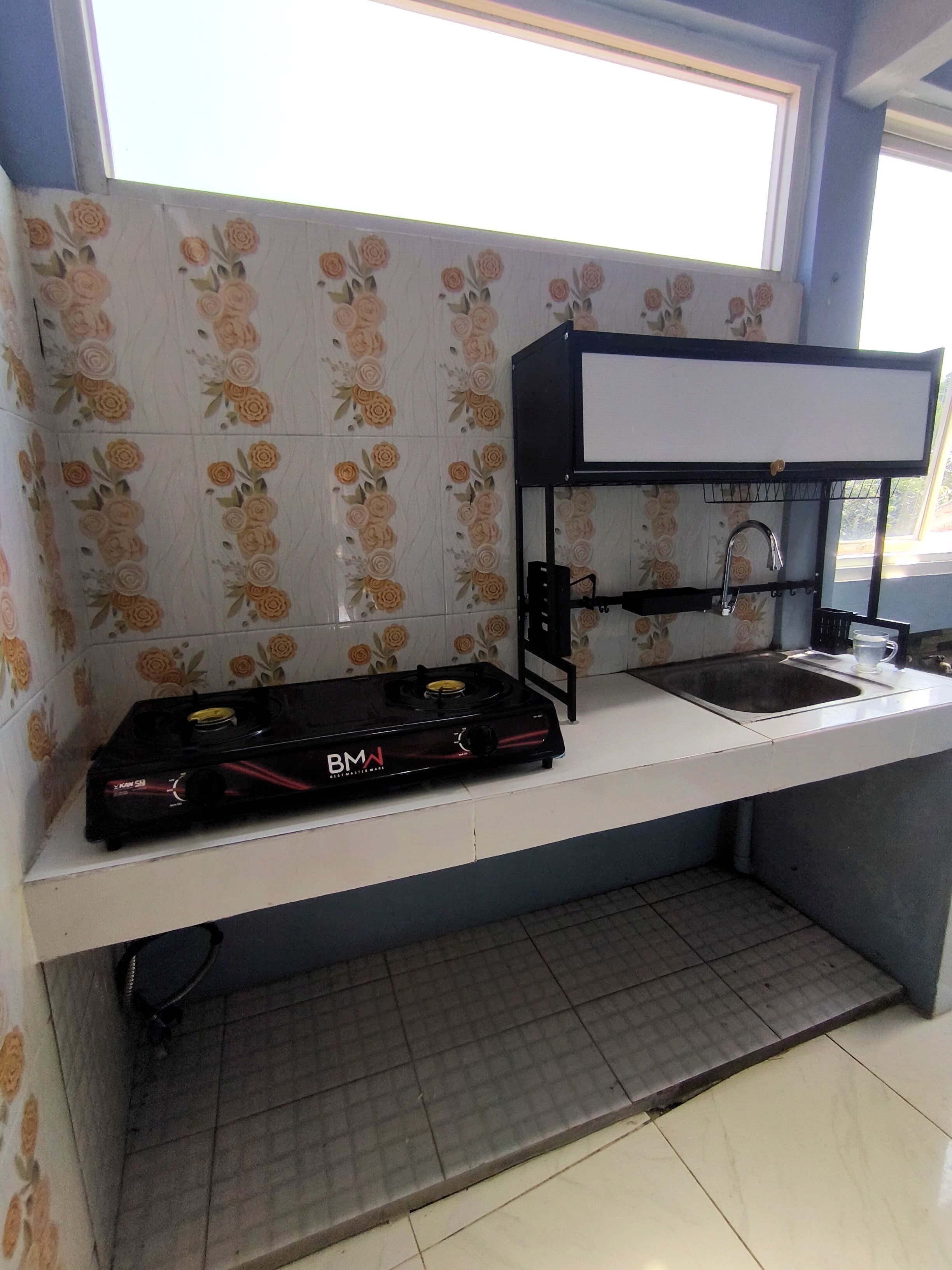 Una cocina con estufa a gas, lavamanos y una campana extractora negra.