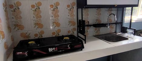 Una cocina con estufa a gas, lavamanos y una campana extractora negra.