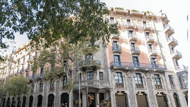 Un edificio histórico de varios pisos, con balcones ornamentados y grandes puertas, probablemente un hotel o edificio público.