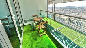 A balcony with a table and chairs, a trash can, and a view of the cityscape. - Cozy 1BR Apartment Nr World Trade Centre (Dubai)