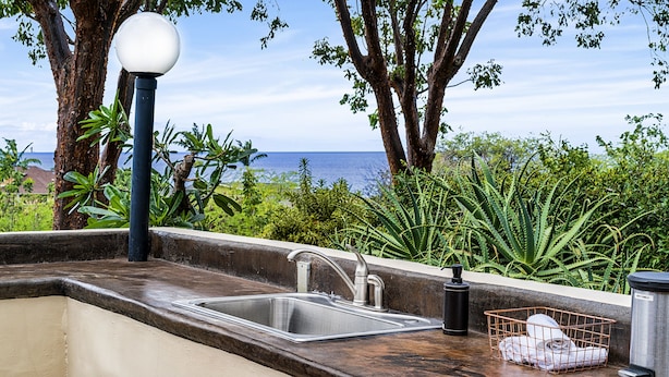 A kitchen with a sink, a black lamp, and a metal container. - Kona Mansions E333 1 Bedroom Condo (Kailua-Kona)