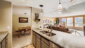 A modern kitchen with granite countertops, stainless steel appliances, and a dining area with wooden furniture. - 1806 Decatur 2 Bedroom Condo (Keystone)