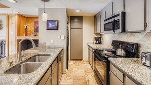 A modern kitchen with granite countertops, stainless steel appliances, and a built-in oven. - 1806 Decatur 2 Bedroom Condo (Keystone)
