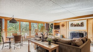 A cozy living room with a sofa, a table, and a TV. There is a fireplace and a sign that says "friends". - 1806 Decatur 2 Bedroom Condo (Keystone)