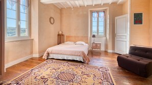 Un dormitorio con cama, mesita de noche, cómoda, ventana y puerta.