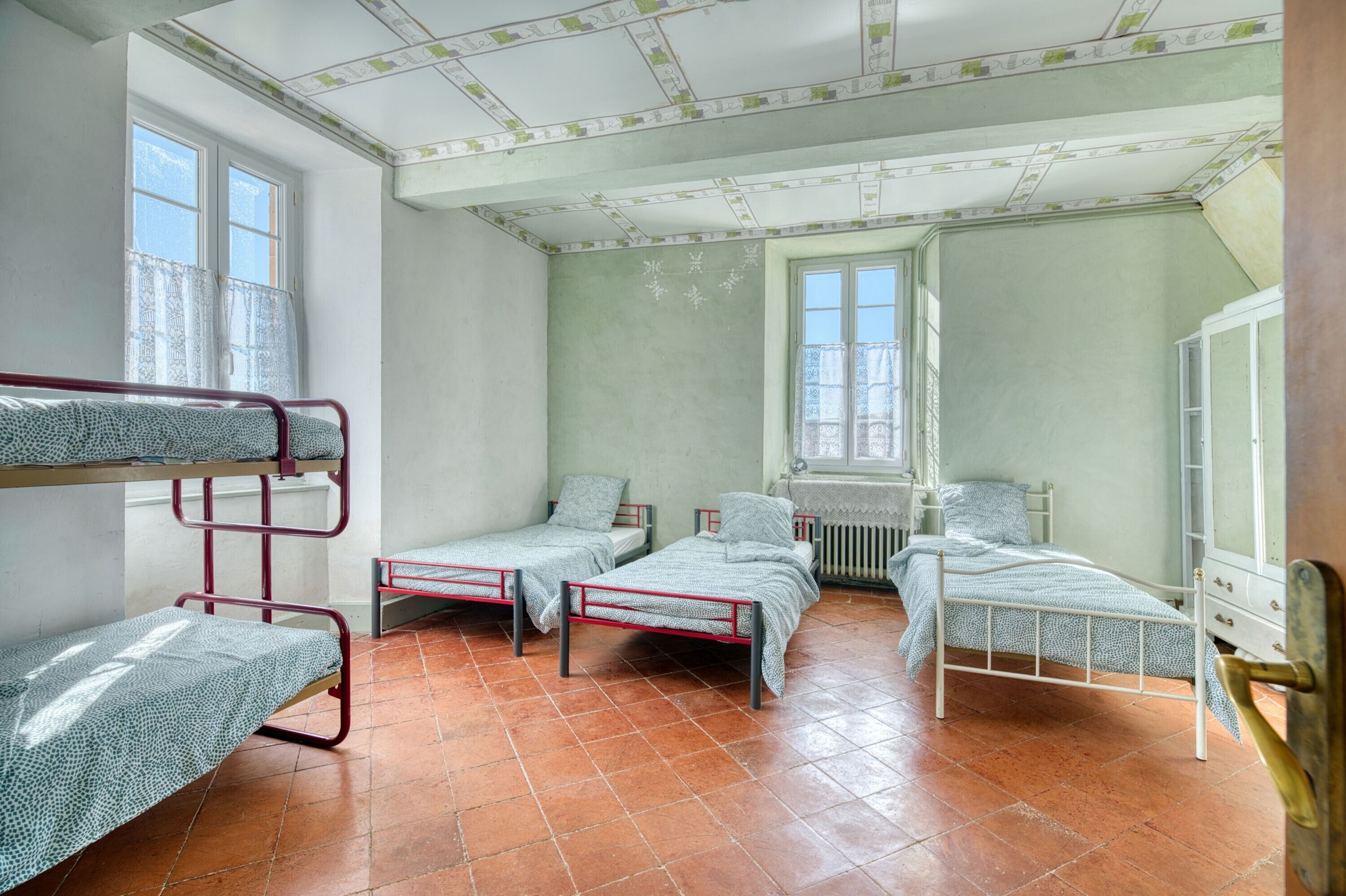 Una camera del dormitorio con letti a castello, una finestra, un termosifone e un armadio.