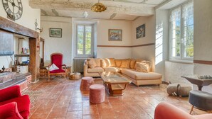 Un salón espacioso con un sofá grande, un sillón rojo, una mesa de centro de madera y una chimenea.