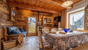 Een rustiek houten interieur met een eettafel, stoelen, een televisie en een open haard.