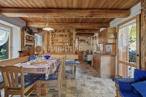 Un interior rústico de madera con una mesa de comedor, sillas y una zona de cocina.