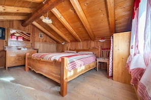 Une chambre dans une cabane en bois, avec un lit, une commode et une petite table.