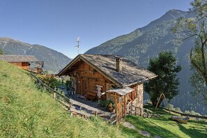 Un chalet en bois avec un toit en pente, une véranda en bois et une cheminée en pierre.