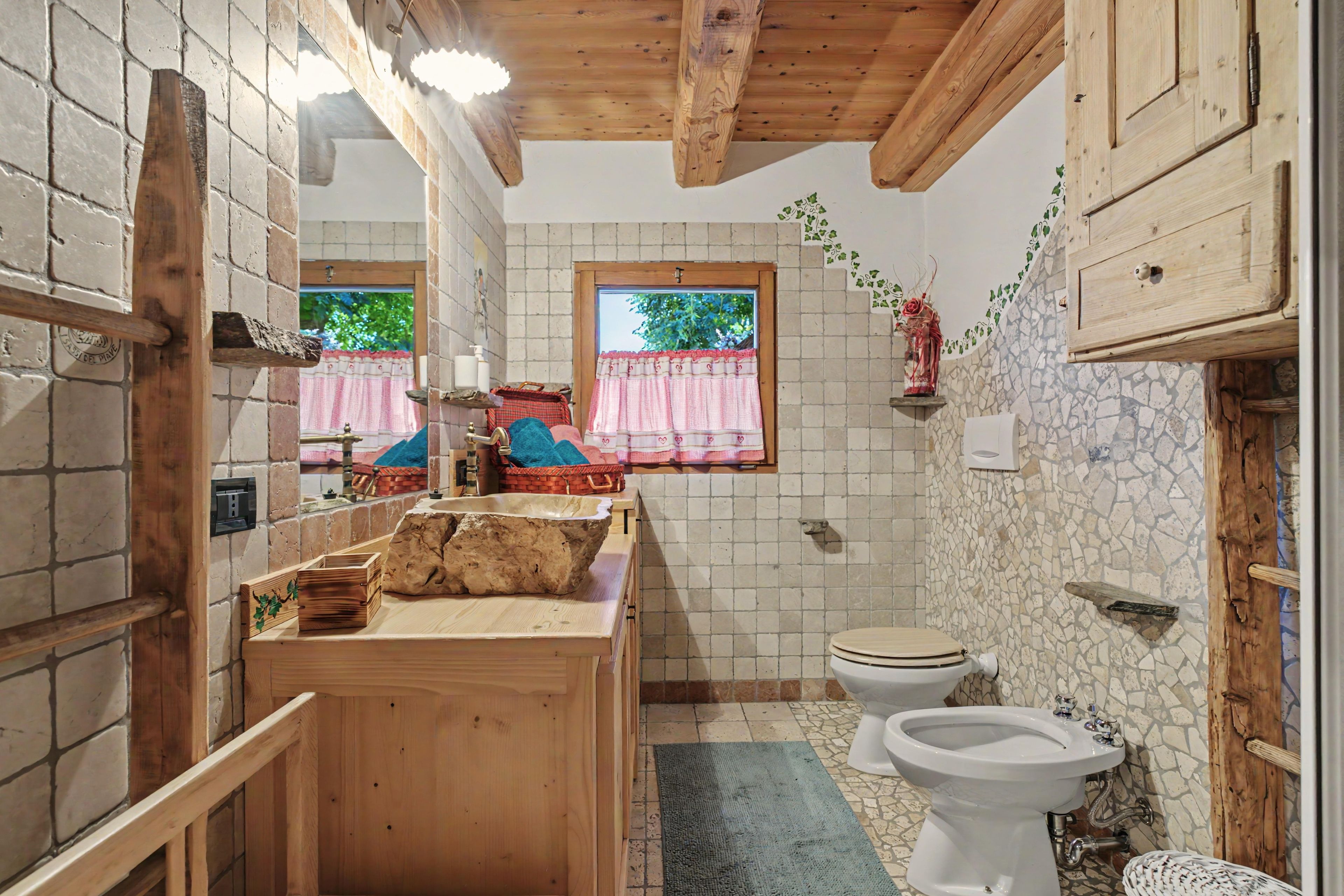 Un baño rústico con un tocador de madera, inodoro y bidé.