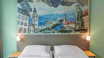 Une chambre d’hôtel avec deux lits, une fresque murale et une petite table.