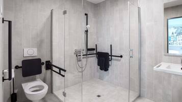 A modern bathroom with a glass-enclosed shower, a toilet, and a sink.