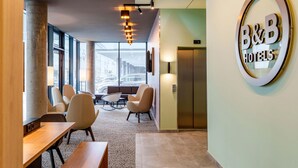 A B&B hotel lobby with a reception desk, seating area, and an elevator.