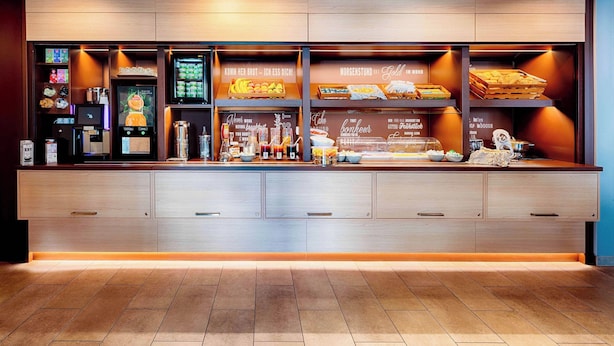A breakfast bar with a variety of food and drink options, including fruits, pastries, and beverages.