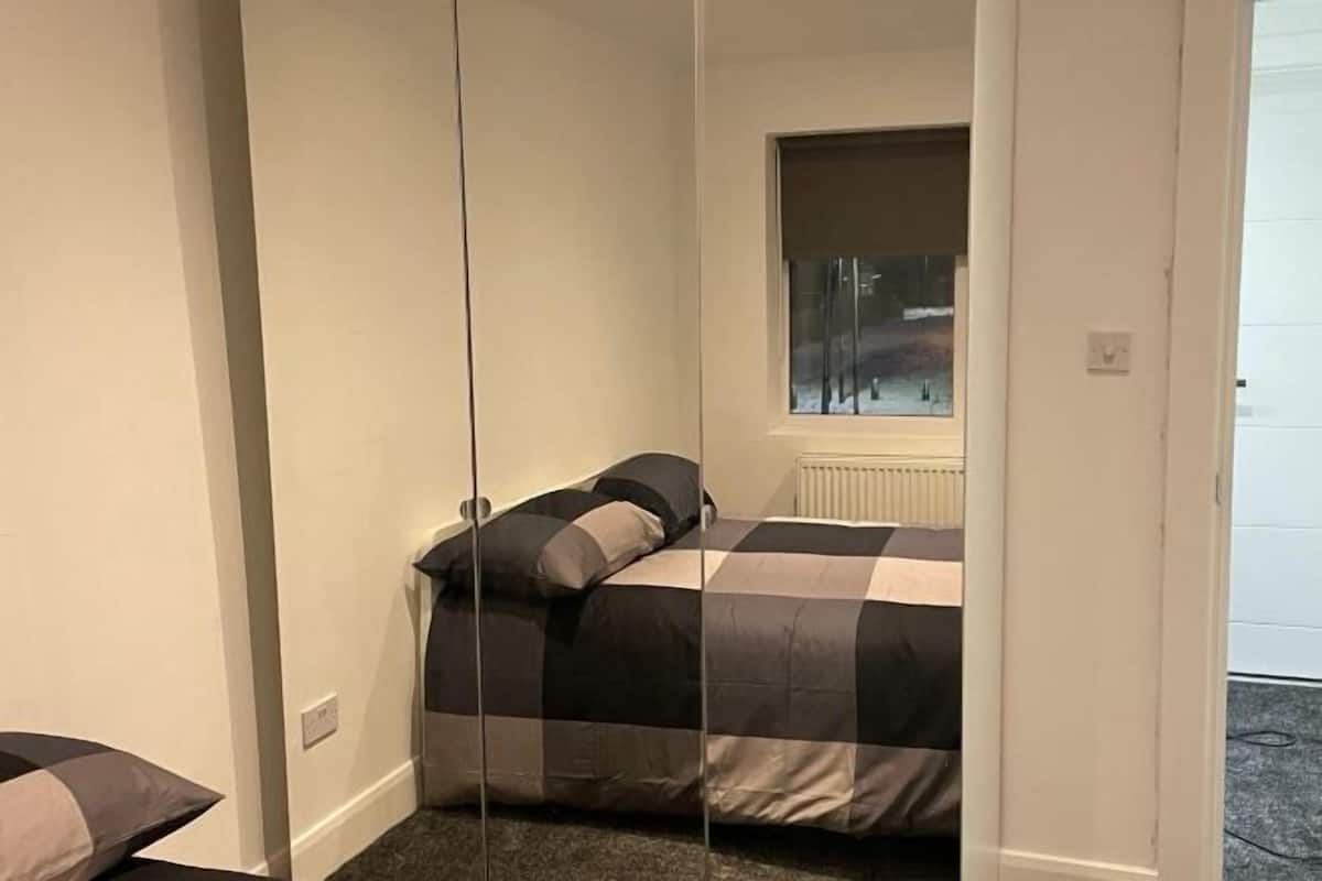 A bedroom with a bed, a window, and a radiator.