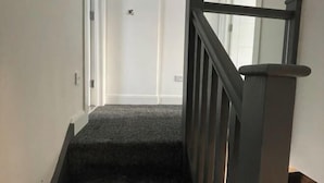A carpeted staircase with a dark handrail and white walls. - Greenwich Oasis Near o2 arena with Spacious Charm (Greenwich)
