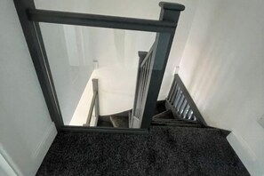 A staircase with a dark carpeted floor and a metal railing. - Greenwich Oasis Near o2 arena with Spacious Charm (Greenwich)