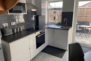 A compact kitchen with a black countertop, white cabinets, a built-in oven, and a window overlooking a backyard. - Greenwich Oasis Near o2 arena with Spacious Charm (Greenwich)