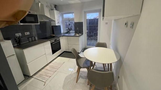 A compact kitchen with a dining area, a microwave, a stove, and a window. - Greenwich Oasis Near o2 arena with Spacious Charm (Greenwich)
