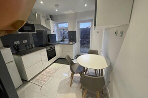 A compact kitchen with a dining area, a microwave, a stove, and a window. - Greenwich Oasis Near o2 arena with Spacious Charm (Greenwich)