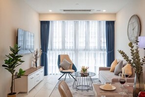 Una sala moderna con sofá, sillón, mesa de comedor y televisor montado en la pared.