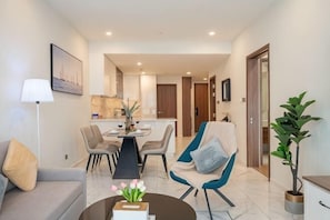 Una sala de estar moderna con sofá, sillón, mesa de centro y comedor con sillas y mesa.