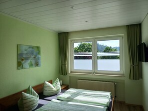 Une chambre à coucher avec un lit, une fenêtre, un radiateur et un tableau accroché au mur.