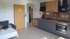 A modern kitchen with grey cabinets, a wooden countertop, a built-in oven, and a coffee maker.