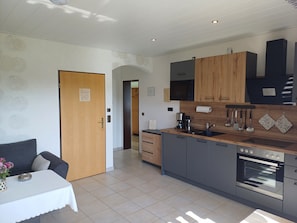 A modern kitchen with grey cabinets, a wooden countertop, a built-in oven, and a coffee maker.