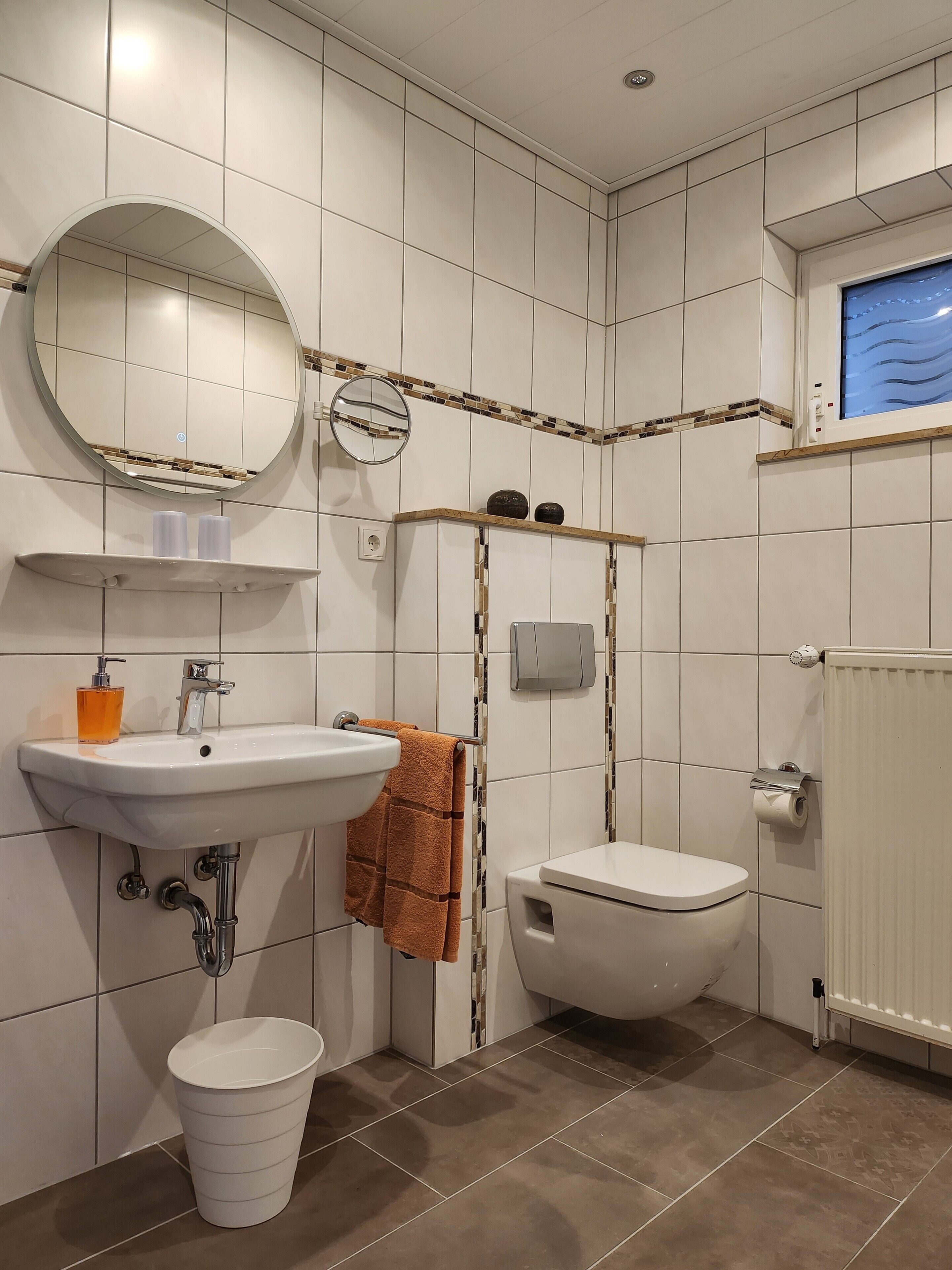 Une salle de bain avec un lavabo, un miroir, des toilettes et une fenêtre.