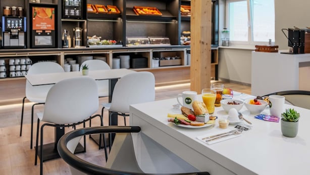 A modern breakfast area with a counter, seating, and a coffee station. - B&B Hotel Mittenwald (Mittenwald)