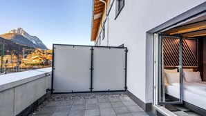A modern hotel room with a large sliding glass door leading to a balcony, a bed with white linens, and a view of a mountain. - B&B Hotel Mittenwald (Mittenwald)