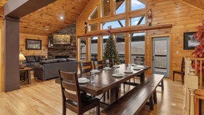 Eine geräumige Holzhütte mit Essbereich, Kamin und Weihnachtsbaum.
