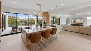 Una cocina moderna con una isla grande, taburetes de bar y una zona de comedor con sofá.
