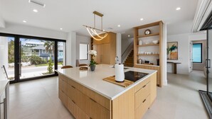 Una cocina moderna con una isla grande, armarios de madera y vistas al exterior.