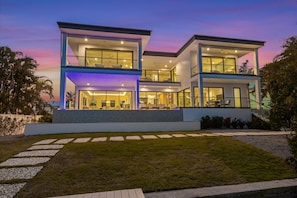A modern two-story house with large windows, a balcony, and a well-maintained lawn.