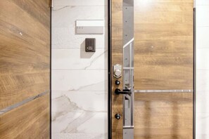 A hotel room with a wooden door, a marble wall, and a number plate indicating room 302.