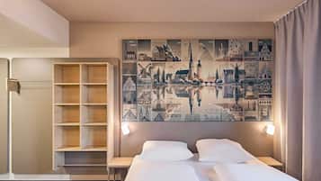 Habitación de hotel con cama, mesitas de noche, armario y una pared decorada con una obra de arte urbana.