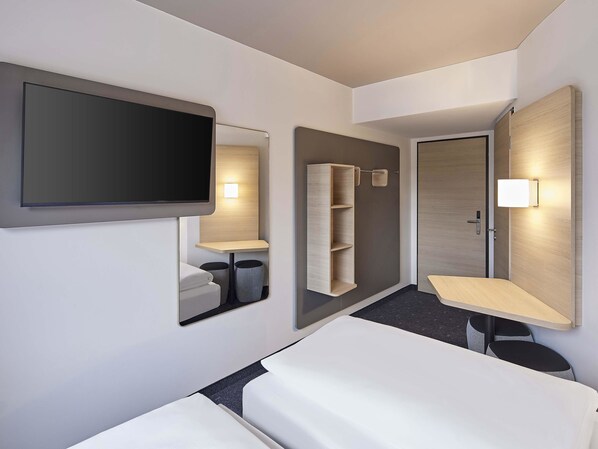 Una habitación de hotel moderna con una televisión de pantalla plana grande, una mesita de noche, un espejo y un armario.